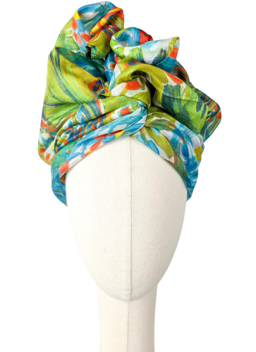 Green silk turban with a painterly print in turquoise lime orange and yellow – front view on a mannequin head – Glinkowska