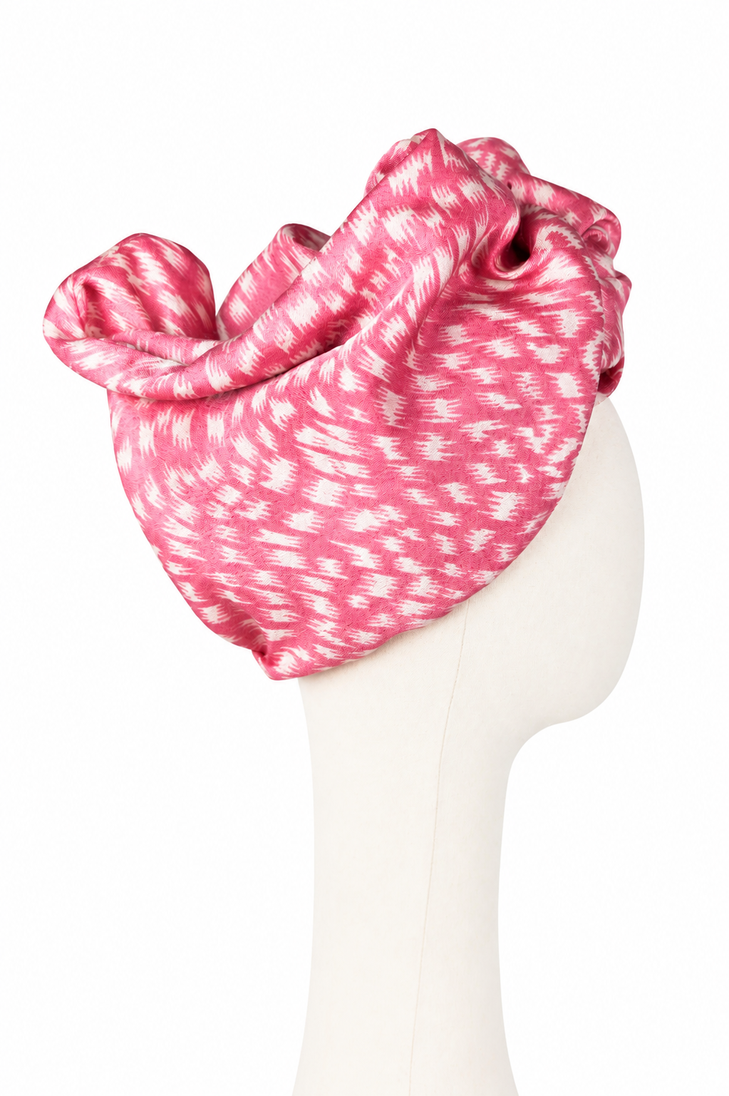 Prawy profil kremowego manekina w różowym turbanie Twist Long z pashminy i jedwabiu. Materiał układa się w szerokie, falujące fałdy i miękkie łuki wokół głowy. Tkanina jest malinoworóżowa z jasnym, nieregularnym drukiem przypominającym krótkie smugi pędzla i cętki. Turban zakrywa całą górę głowy.