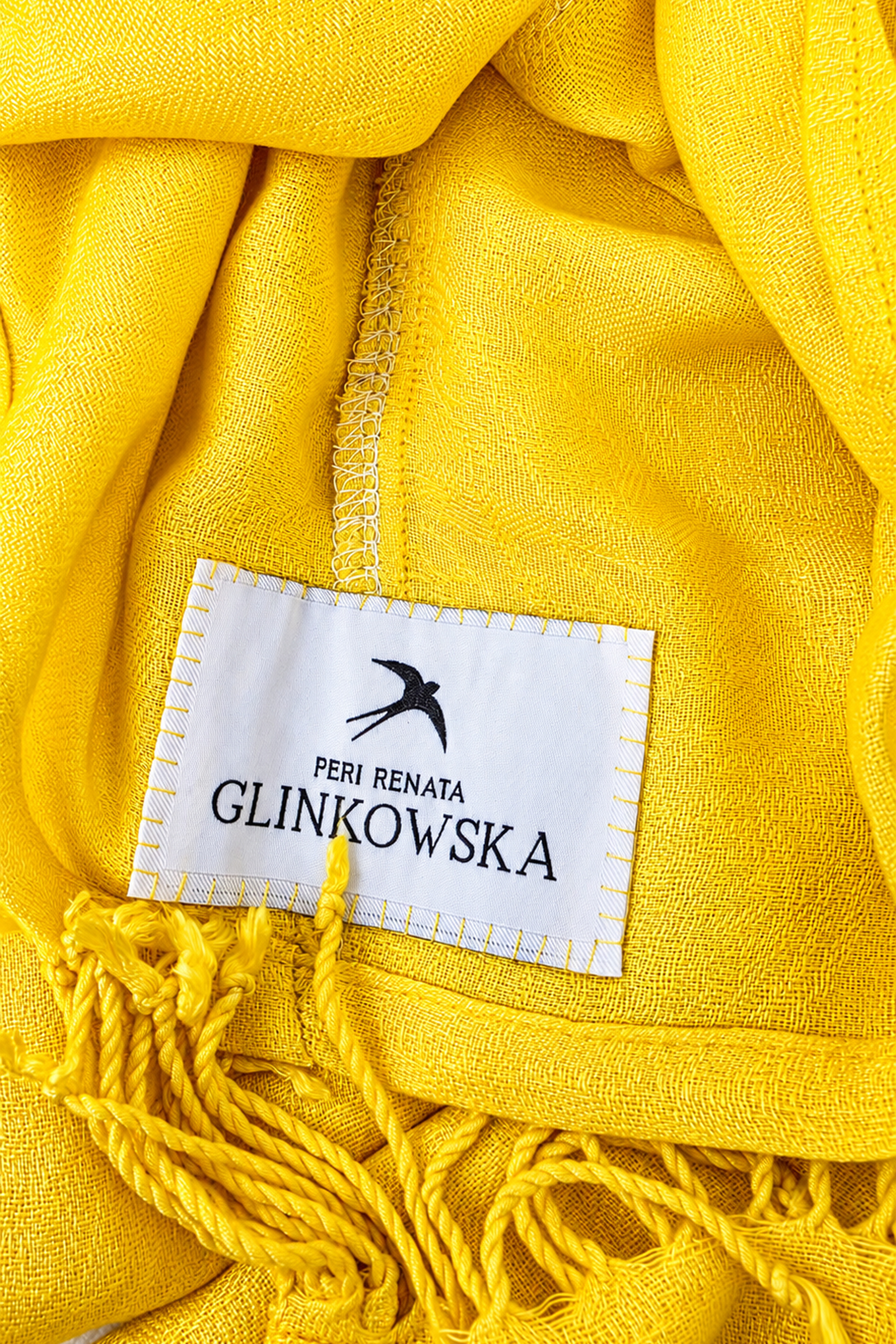 Close-up of the yellow jacquard turban fabric, fringes and PERI Renata Glinkowska brand label.