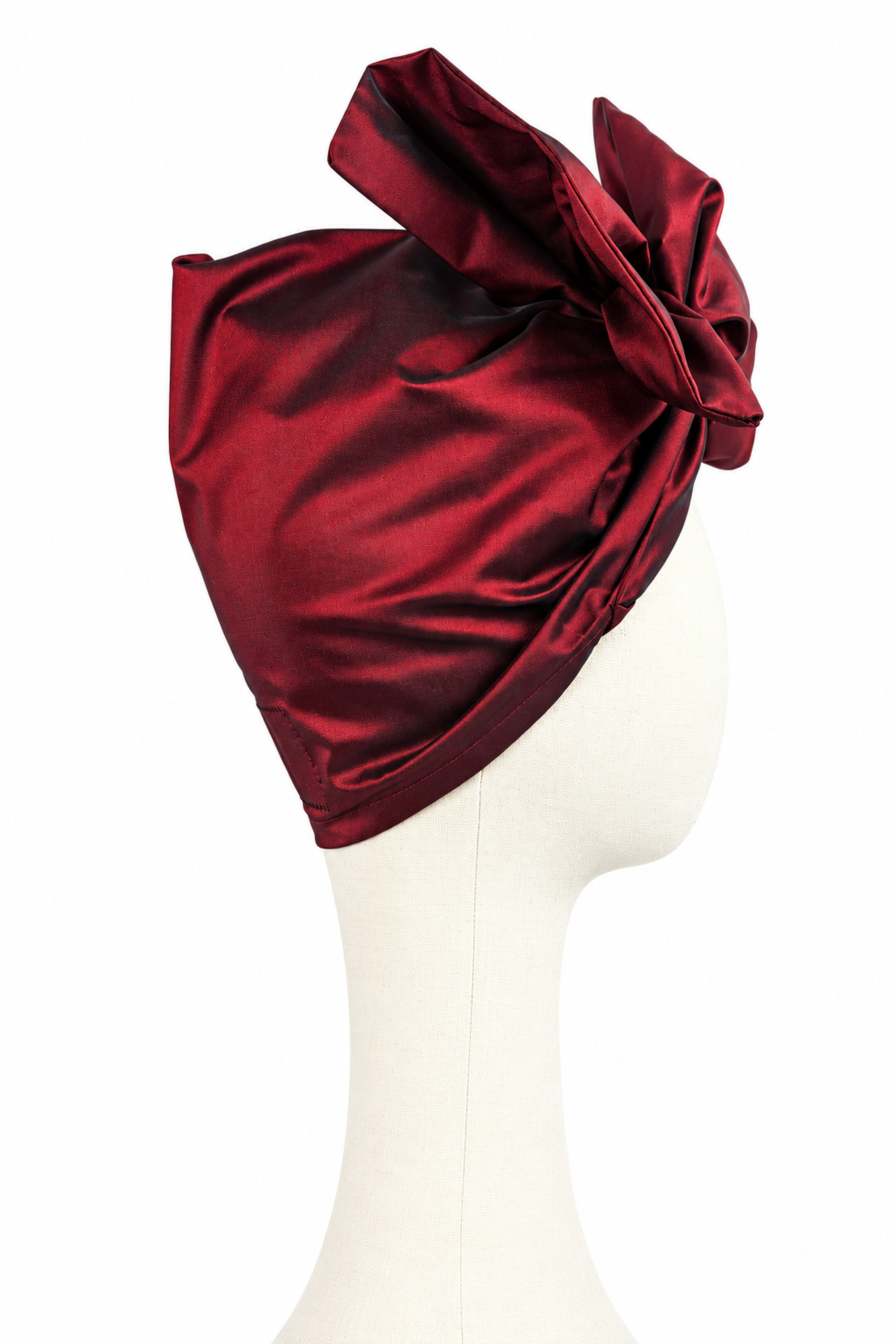 Opposite side view of a women’s short burgundy taffeta Twist evening turban with a sculptural bow.