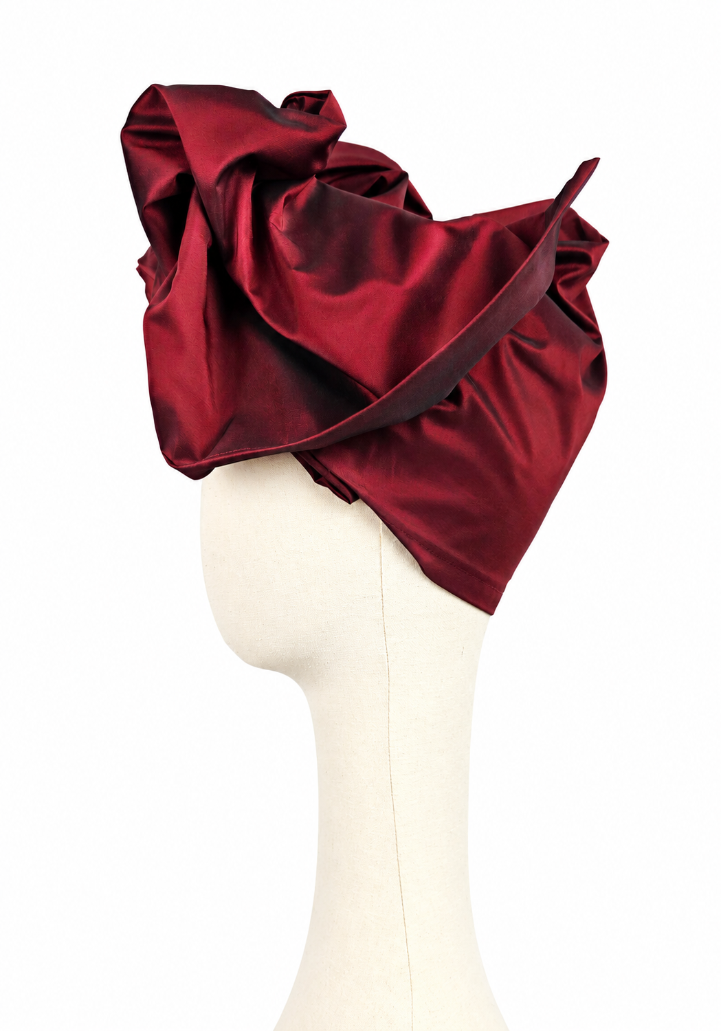 Left-facing side view of a women’s long burgundy taffeta Twist evening turban with flowing sculptural panels.