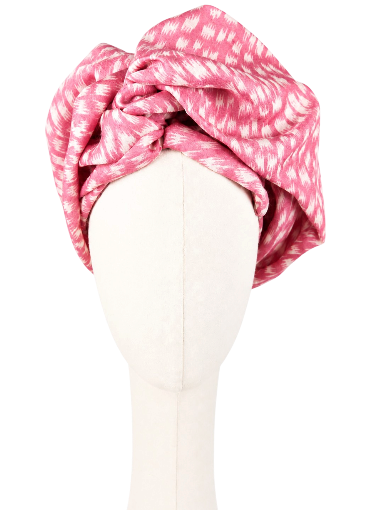 Women's pink Twist Long turban made from pashmina and silk, shown from the front on a cream-colored faceless mannequin. The turban is generously draped high into soft, asymmetrical folds. The raspberry-pink fabric features an irregular white print resembling short brushstrokes and spots. Light, solid-colored background.