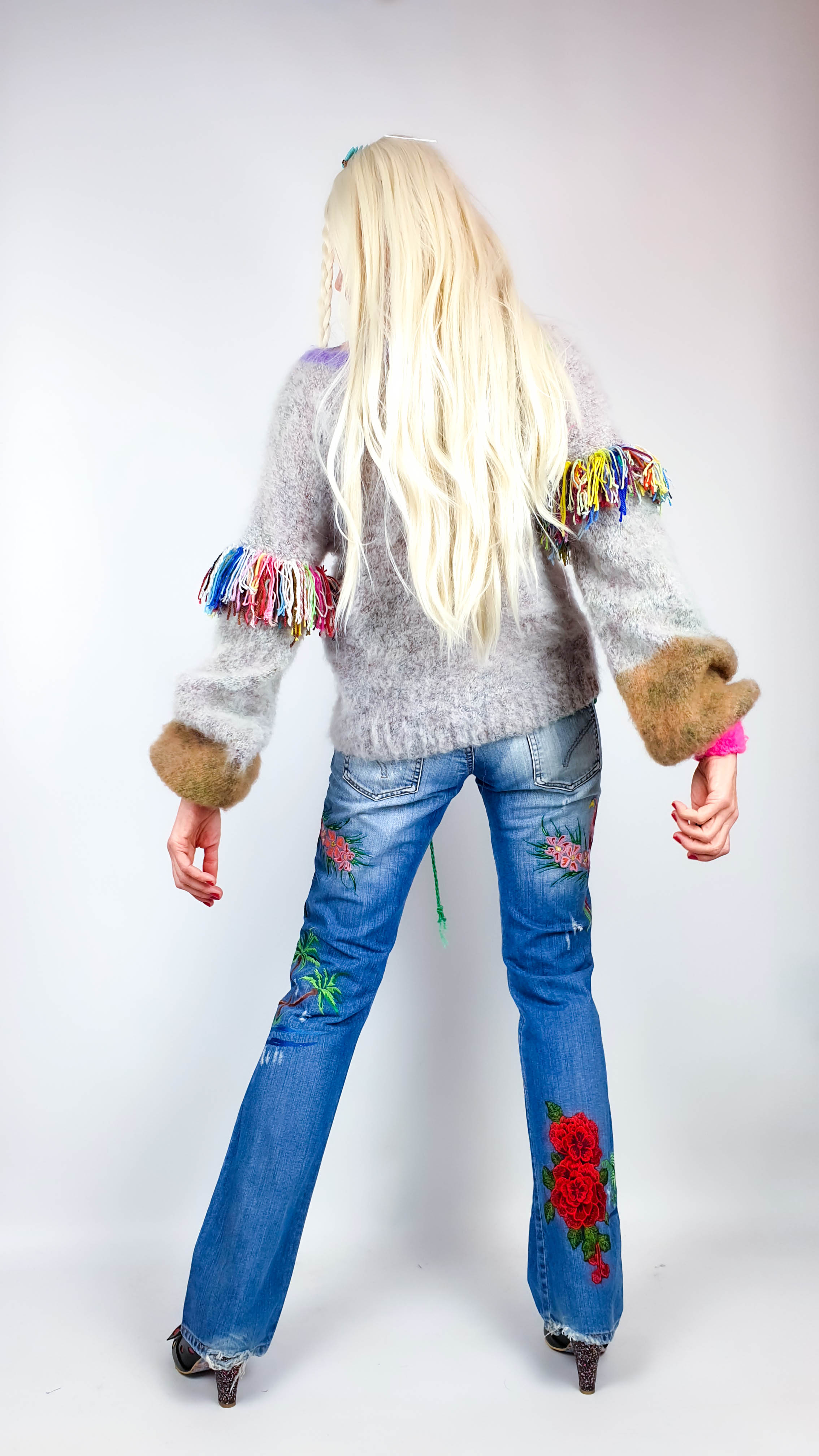 Back view of a woman wearing the fluffy gray oversize sweater with fringed sleeves and camel forearms.